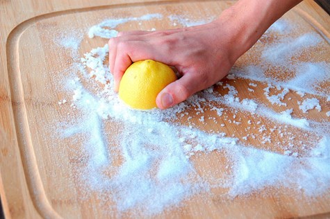 hånd gnider citron mod skærebræt dækket med salt