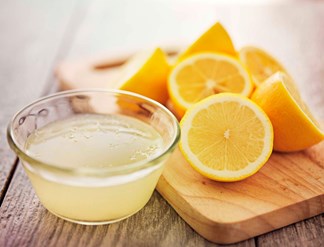 en skål med citronsaft og seks halve citroner på et skærebræt
